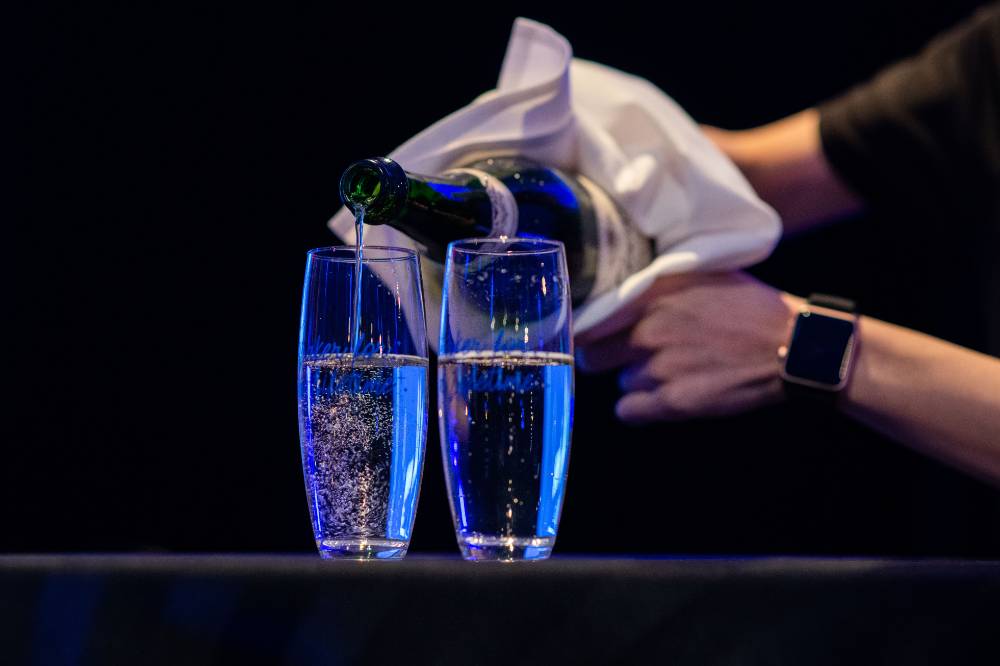 A volunteer pouring champagne into the glasses.